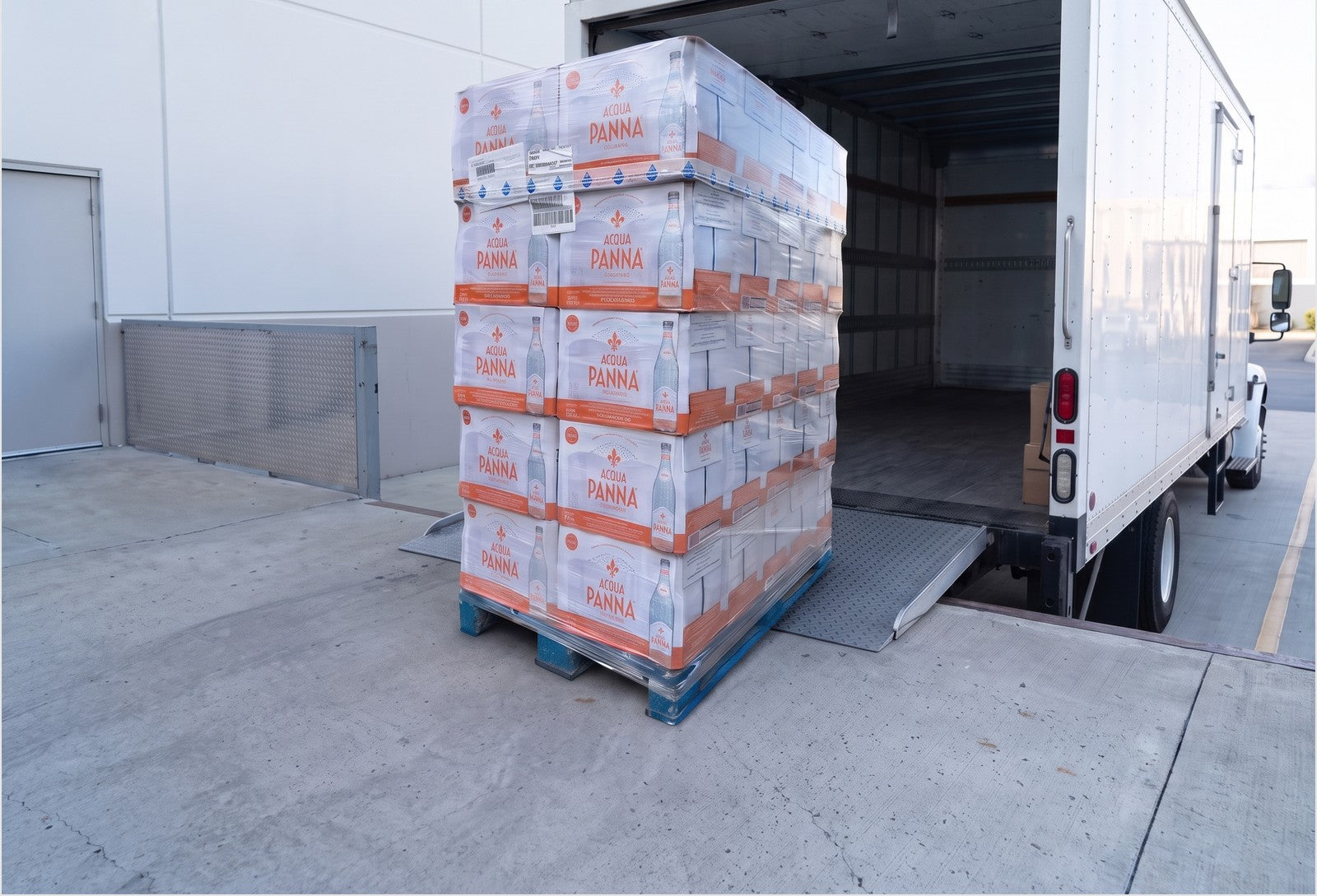 A shrink-wrapped pallet of bottled water being loaded onto a freight truck